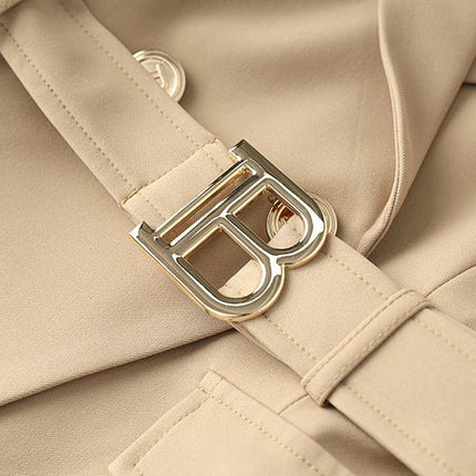 Beige tailored double-breasted jacket with gold button accents and belted waist