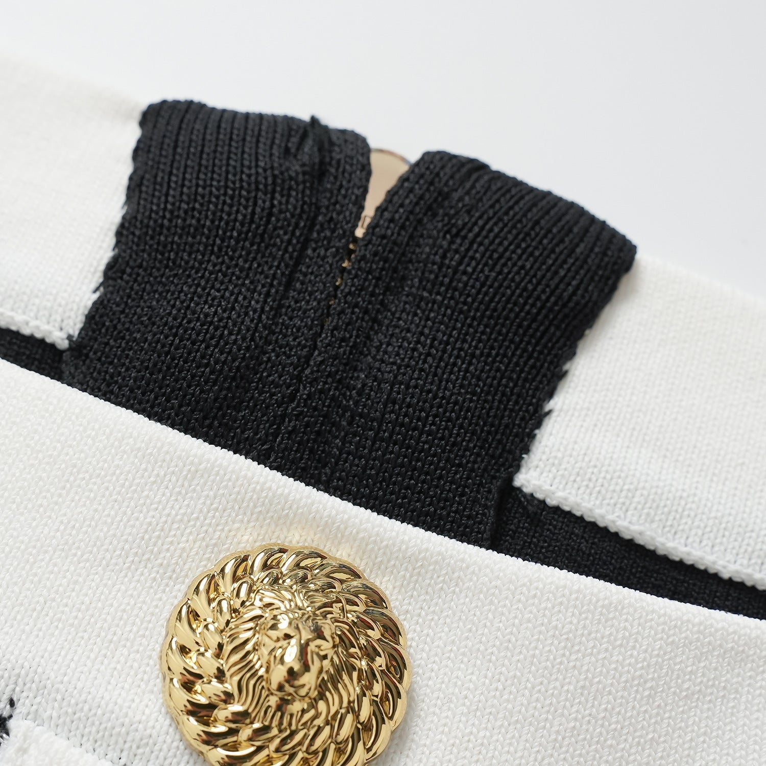 Black bodycon dress with white panel detailing and gold button embellishments