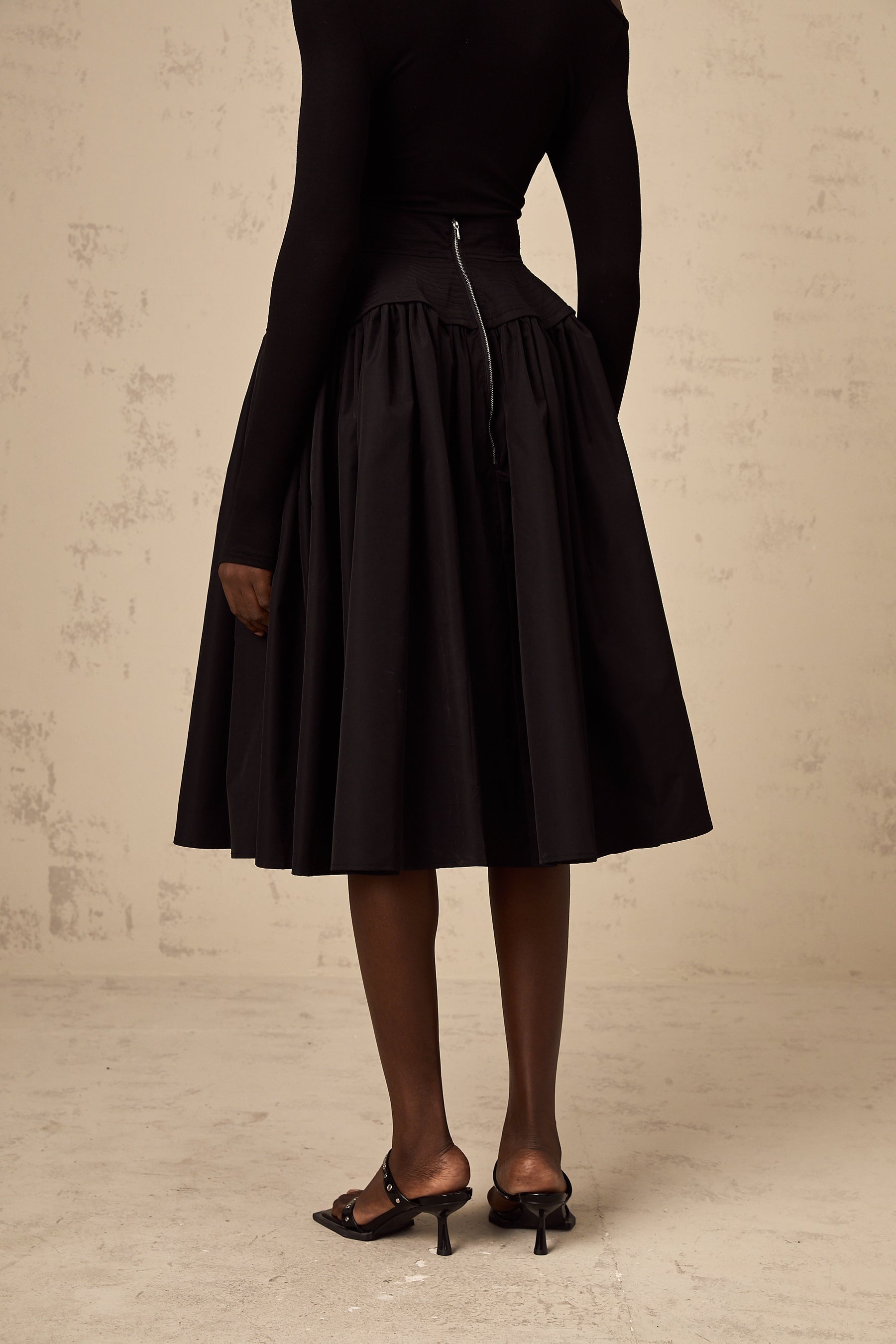 Black pleated midi skirt with flared silhouette named Pauline