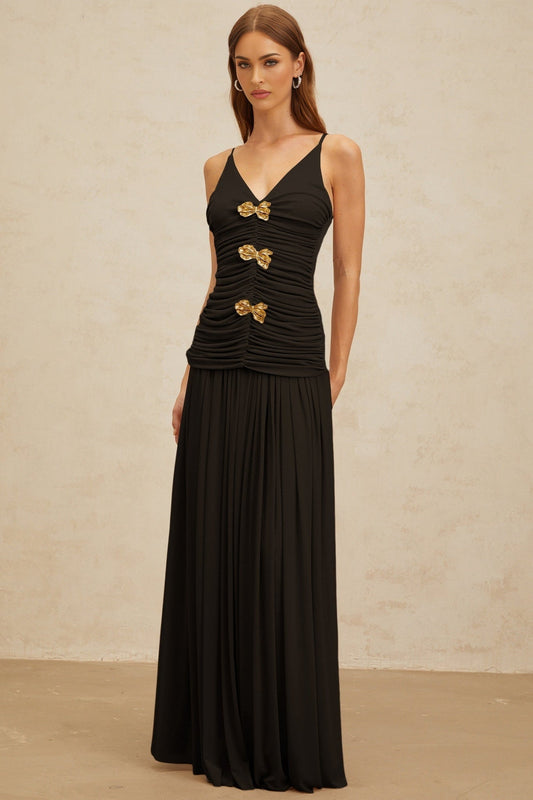 Black V-neck sleeveless top with brooch and ruched detailing, adjustable spaghetti straps, and rear zip fastening, paired with black pleated maxi skirt with rear zip fastening