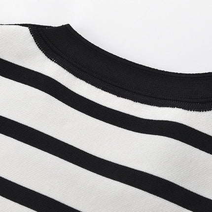 Black and white striped sleeveless body-con dress with gold button accents on shoulders