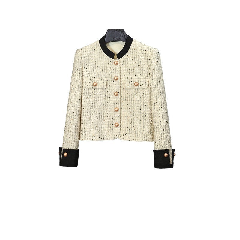 White tweed jacket with pearl buttons and contrasting cuffs, paired with a pleated black high-waisted skirt