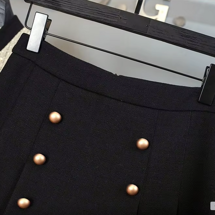 White tweed jacket with pearl buttons and contrasting cuffs, paired with a pleated black high-waisted skirt