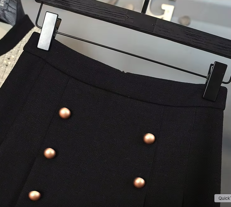 White tweed jacket with pearl buttons and contrasting cuffs, paired with a pleated black high-waisted skirt