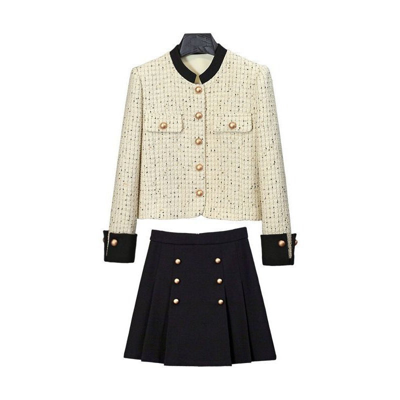 White tweed jacket with pearl buttons and contrasting cuffs, paired with a pleated black high-waisted skirt