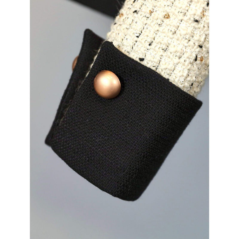 White tweed jacket with pearl buttons and contrasting cuffs, paired with a pleated black high-waisted skirt