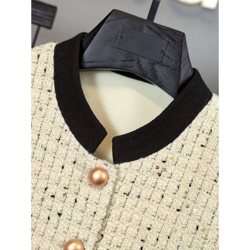 White tweed jacket with pearl buttons and contrasting cuffs, paired with a pleated black high-waisted skirt