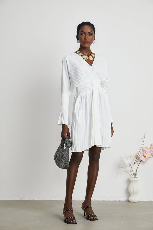 Claudette White Pleated Mini Dress V-neckline Flared Pleated Cuffs Long Sleeves Elegant Feminine Textured Finish Lacing Detail Waist Defined Shape Luxurious Blend Polyester Cotton Light Airy Feel Flowy Mini Length Versatile Timeless Piece