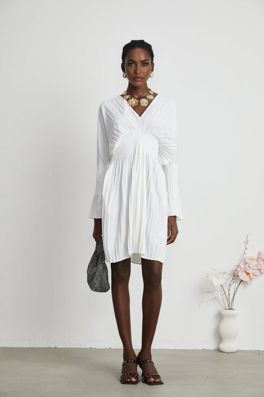 Claudette White Pleated Mini Dress V-Neckline Flared Cuffs Long Sleeves Textured Finish Lacing Detail Waist Defined Shape Luxurious Blend Polyester Cotton Light Airy Feel Elegant Daywear Summer Occasions Chic Gatherings Flowy Mini Length Versatile Timeless Piece