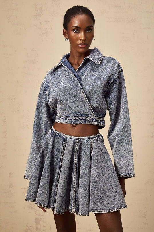 Cropped denim jacket in blue with asymmetrical design and raw hem featuring a single button closure and side pockets