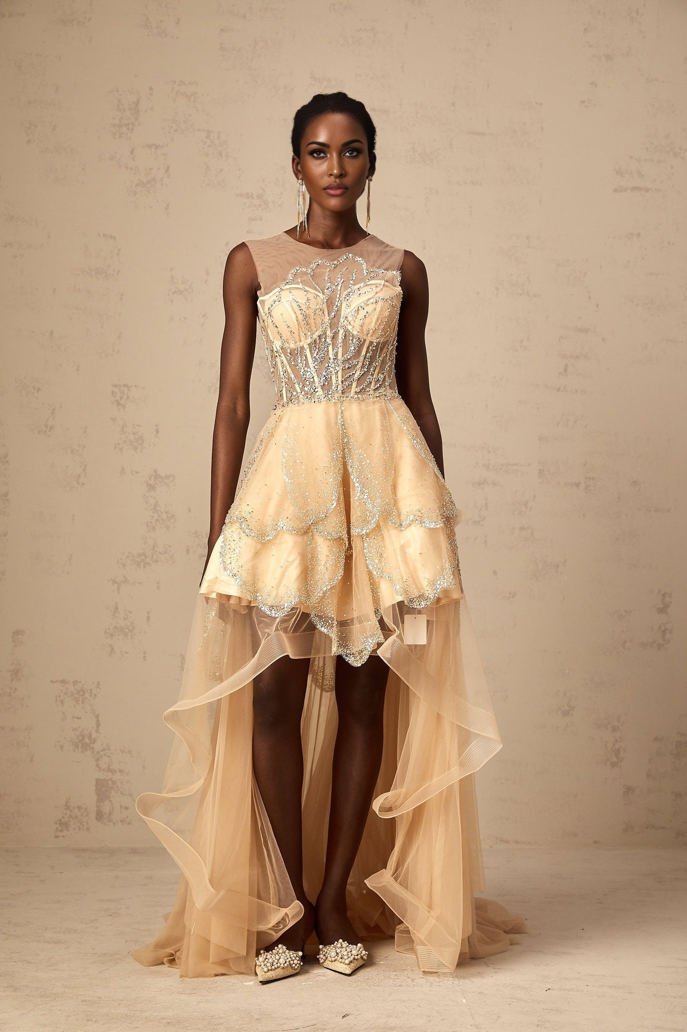 Elegant champagnecolored floorlength gown with daisy embellishments and highlow hemline