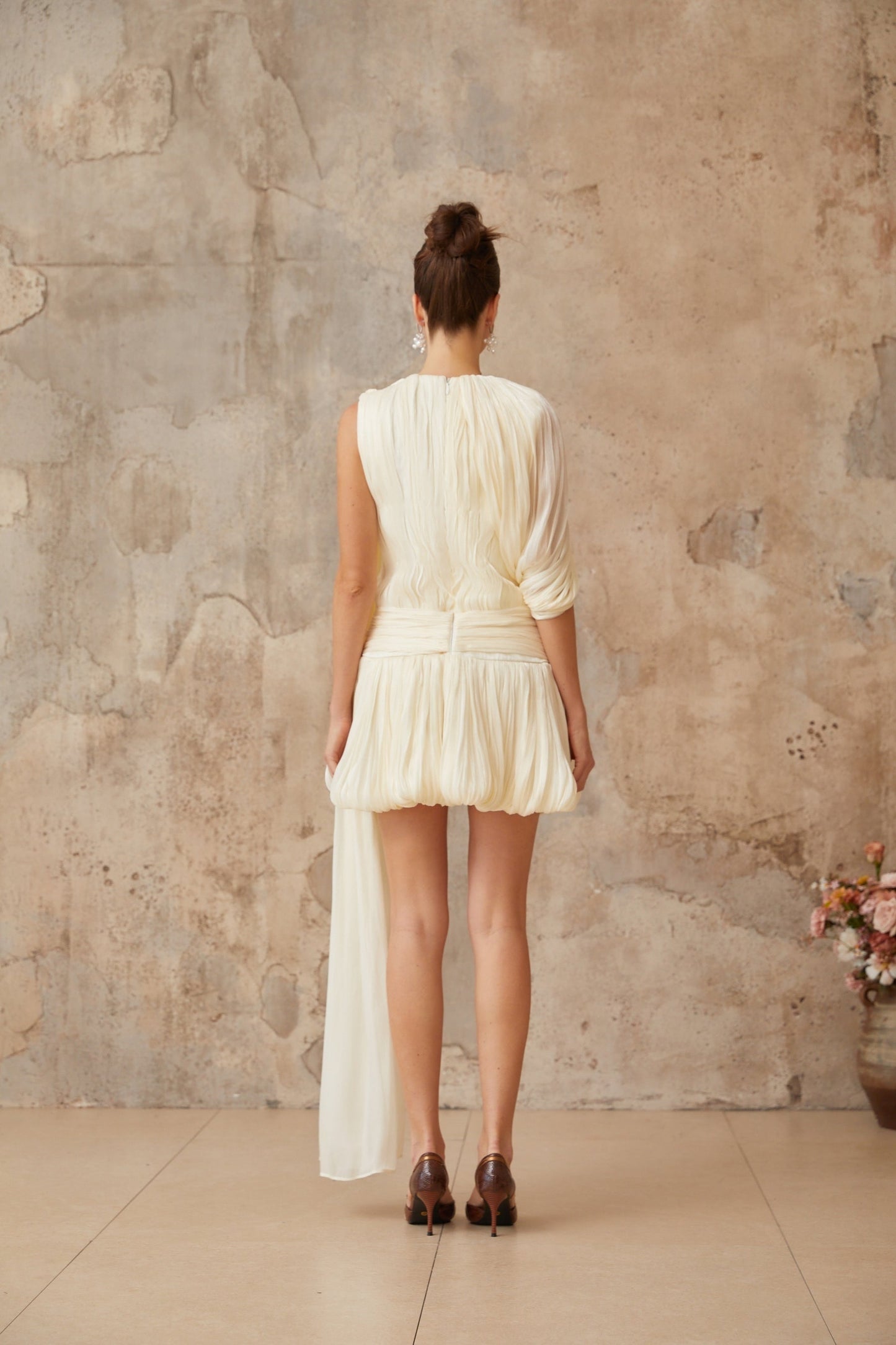 Elegant pleated mini dress in soft fabric with decorative ribbon accents and short sleeves
