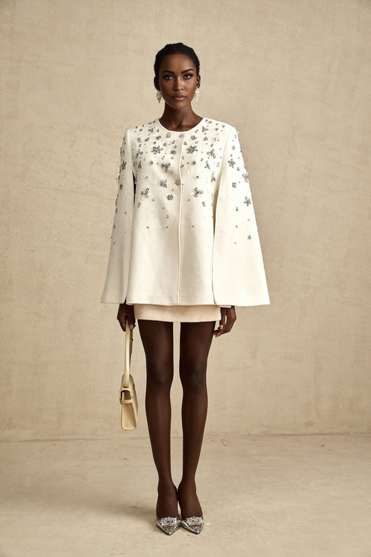 Elegant white jacket with cape design featuring intricate embellishments on shoulders and collar