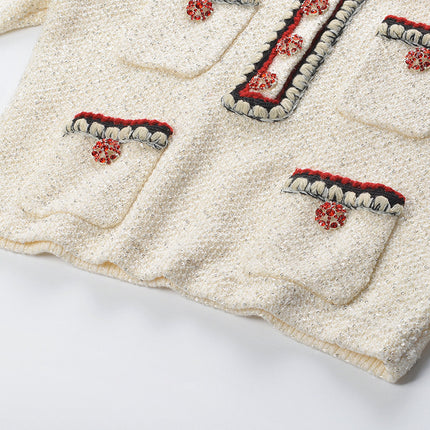 Elegant cream tweed jacket with red and black embroidery, decorative buttons, and a tailored fit