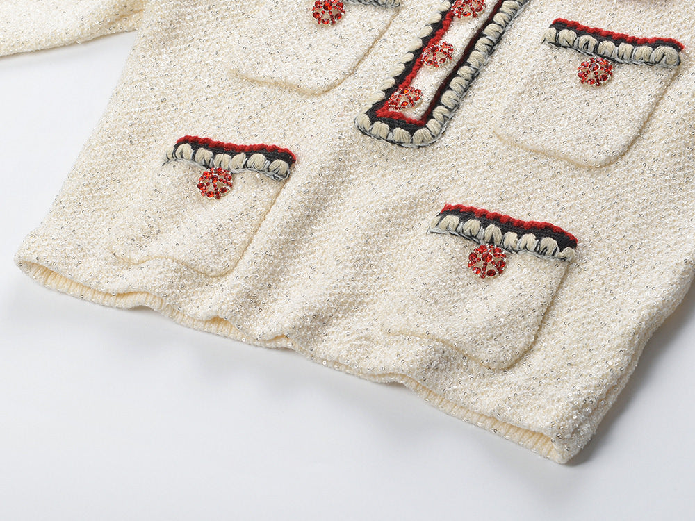 Elegant cream tweed jacket with red and black embroidery, decorative buttons, and a tailored fit