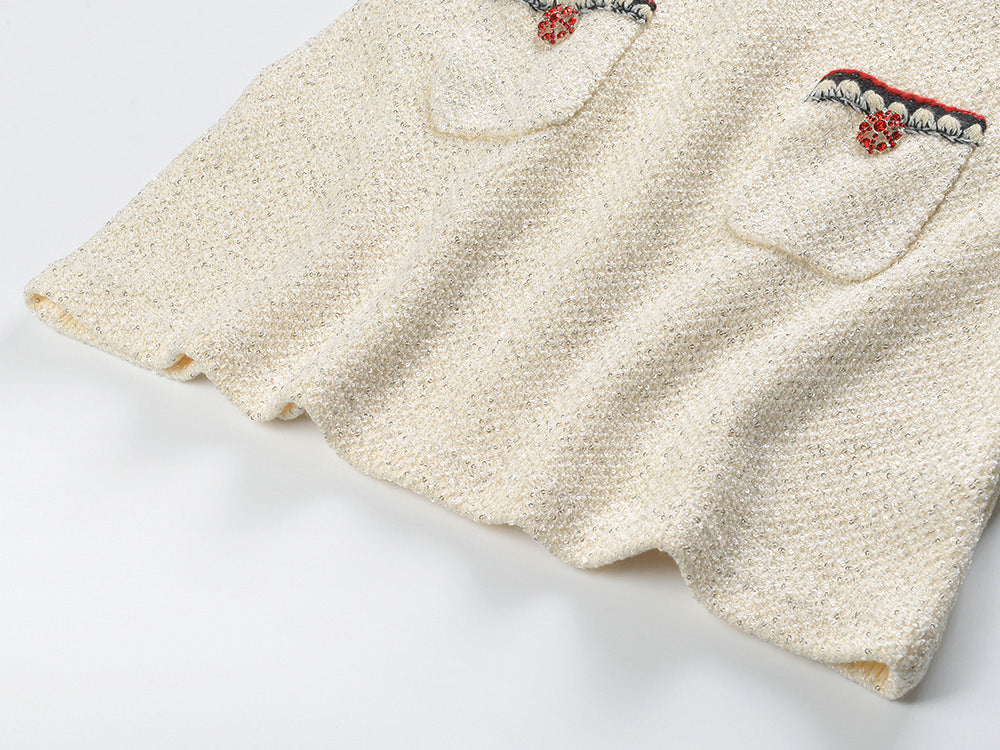 Elegant cream tweed jacket with red and black embroidery, decorative buttons, and a tailored fit