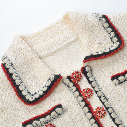 Elegant cream tweed jacket with red and black embroidery, decorative buttons, and a tailored fit