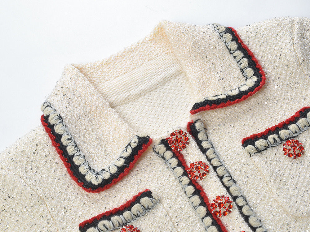 Elegant cream tweed jacket with red and black embroidery, decorative buttons, and a tailored fit