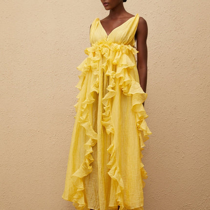Emilia Maxi Dress in Yellow with V-neck, open back, ruffled detailing, asymmetrical hem, and tassel detail
