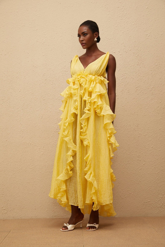 Emilia Maxi Dress in Yellow with V-neck, open back, ruffled detailing, asymmetrical hem, and tassel detail