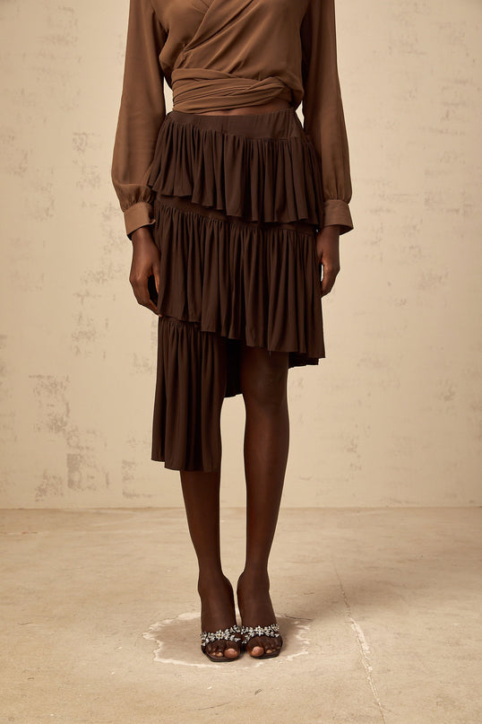 Emma wearing Brown Liora Pleated Tiered Mini Skirt with asymmetrical hem and draped detailing in luxurious Terylene fiber and Spandex blend