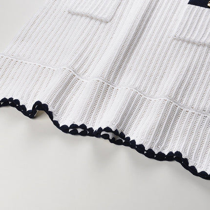 White knit cardigan with navy accents and gold buttons paired with a matching A-line skirt featuring a flared hem