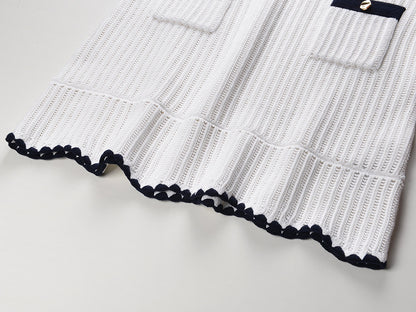 White knit cardigan with navy accents and gold buttons paired with a matching A-line skirt featuring a flared hem