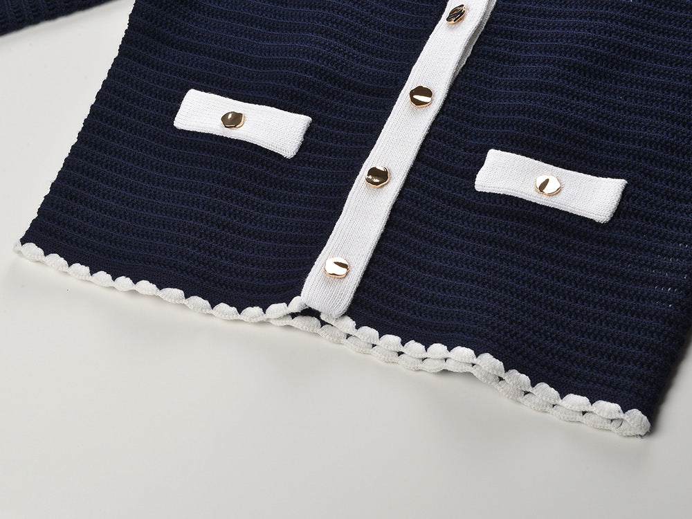 White knit cardigan with navy accents and gold buttons paired with a matching A-line skirt featuring a flared hem