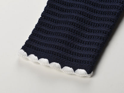 White knit cardigan with navy accents and gold buttons paired with a matching A-line skirt featuring a flared hem