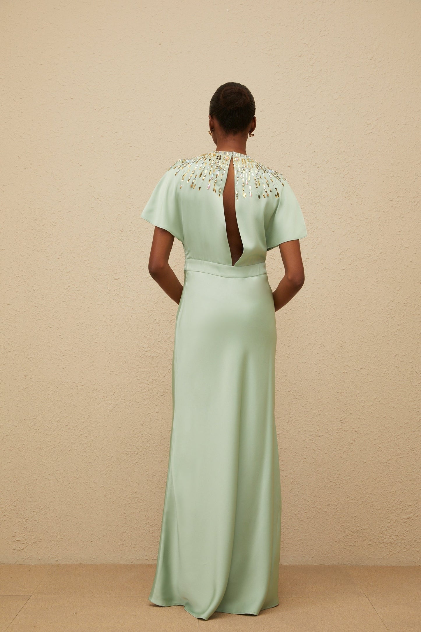 Green maxi dress with sequin, crystal, and bead embellishments, cinched waist, and open back