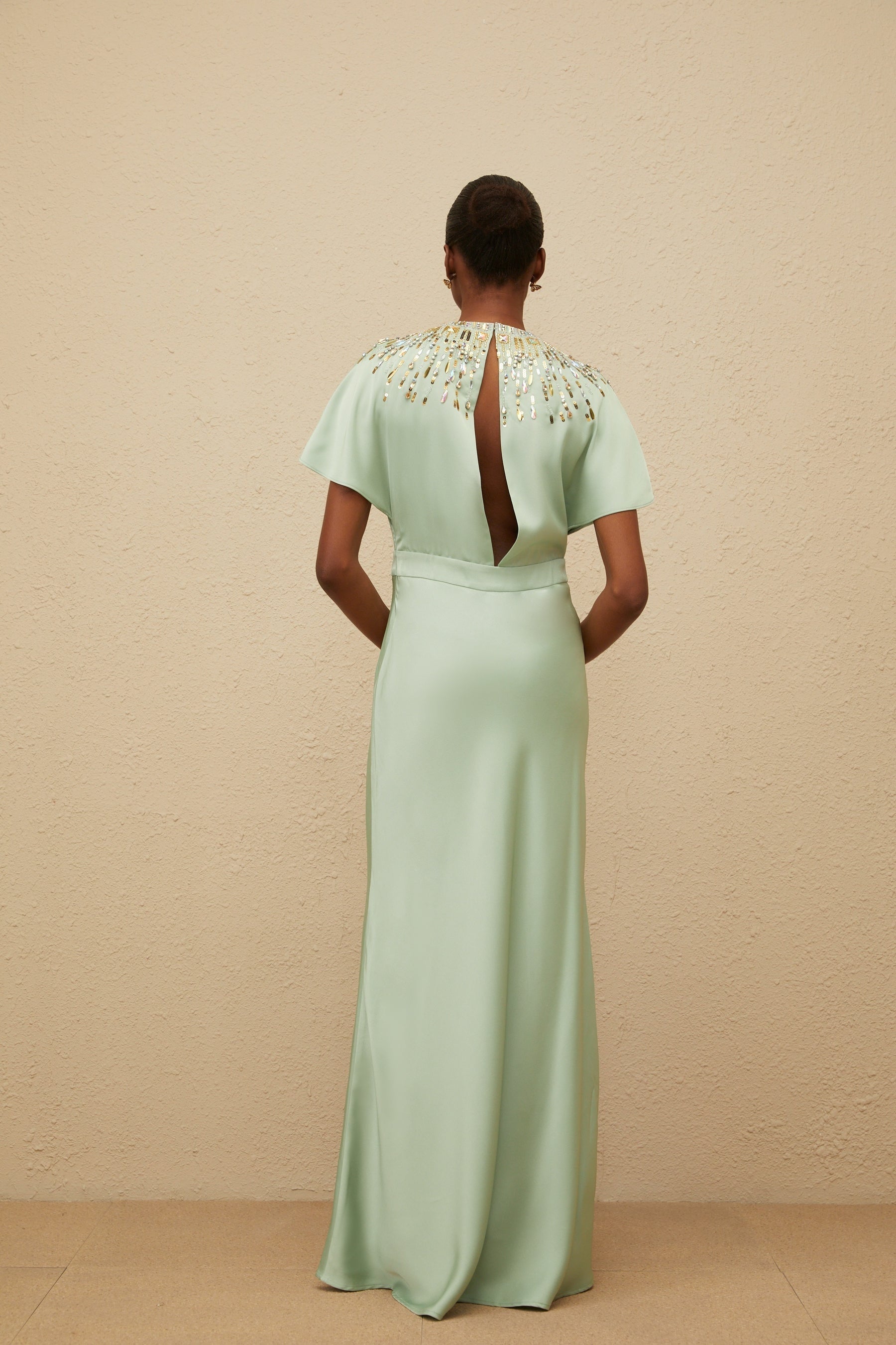 Green maxi dress with sequin, crystal, and bead embellishments, cinched waist, and open back