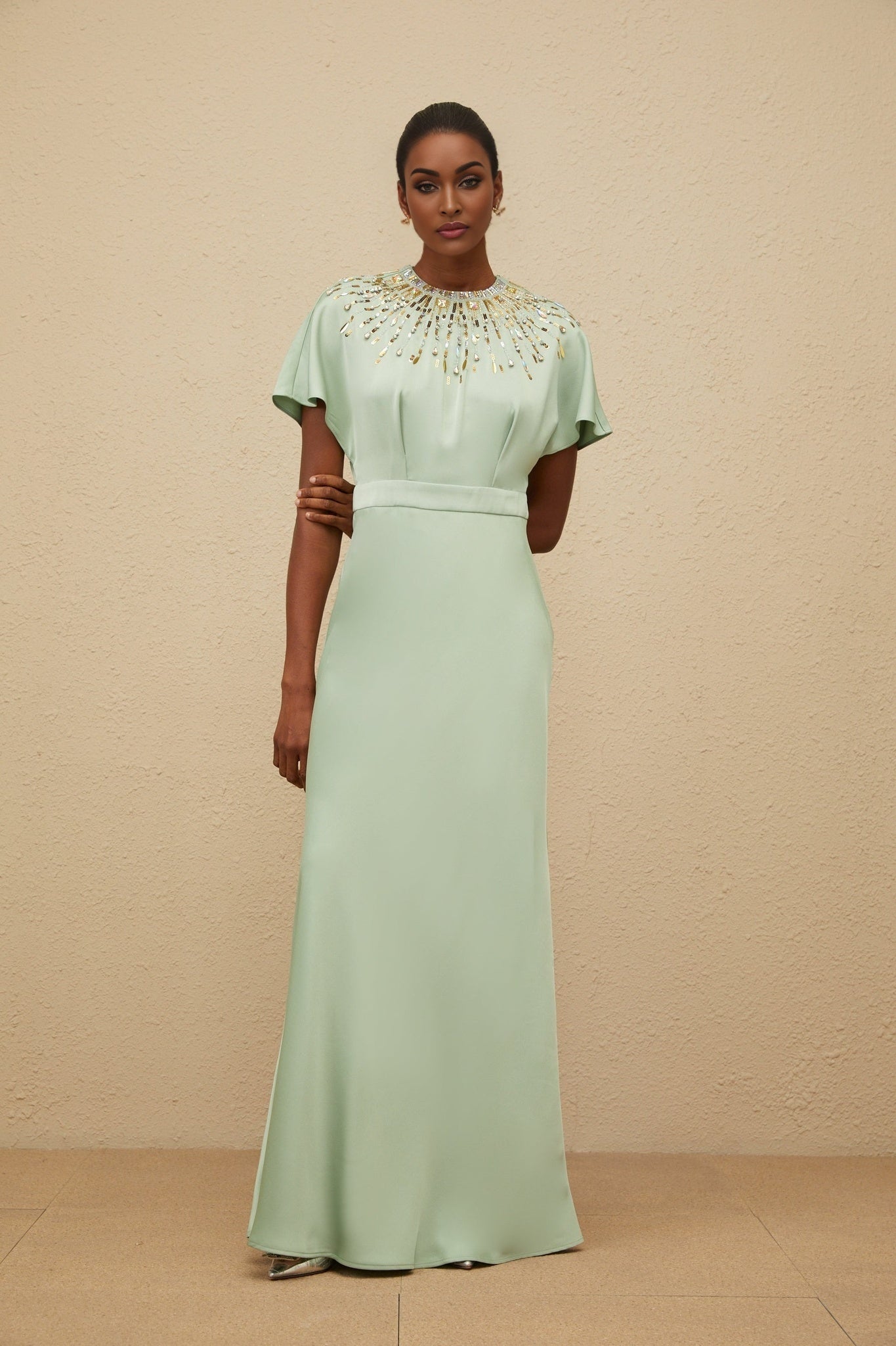 Green satin maxi dress with sequin, crystal, and bead embellishments, cinched waist, and open back