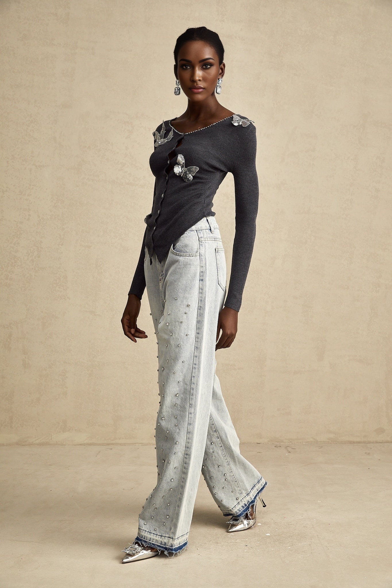 Grey cardigan with sequined butterfly design on front worn by model against plain background