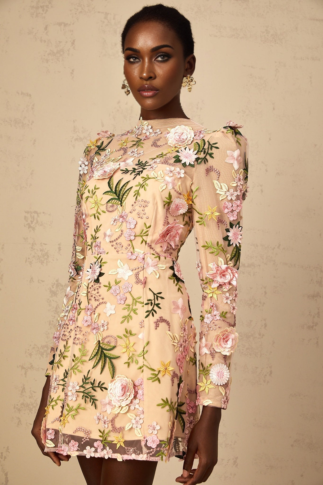 Image of a short pink dress with three dimensional floral applique details covering the bodice and skirt creating a textured and feminine look
