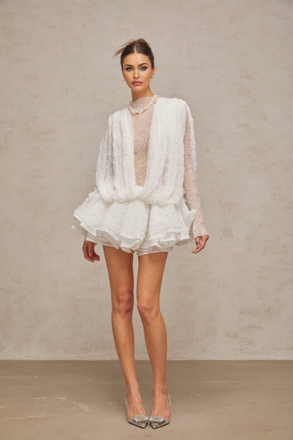 Isoline white lace matching set featuring a semi sheer top shorts and dress laid out on a plain background