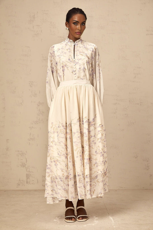 Matching set of light colored shirt and skirt with wisteria floral print and frilled details on a white background