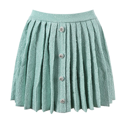 Mint green tweed jacket with floral embellishments paired with a pleated skirt, creating a chic and elegant look
