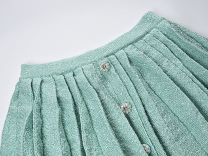 Mint green tweed jacket with floral embellishments paired with a pleated skirt, creating a chic and elegant look