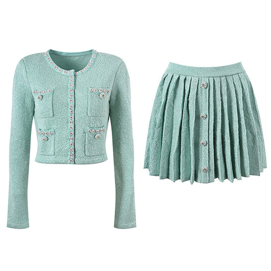 Mint green tweed jacket with floral embellishments paired with a pleated skirt, creating a chic and elegant look