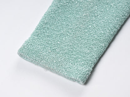 Mint green tweed jacket with floral embellishments paired with a pleated skirt, creating a chic and elegant look