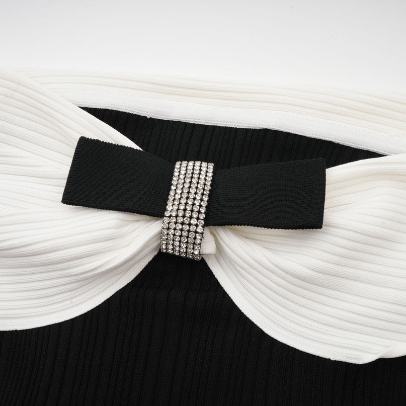 Miracle Mini Dress in Black & White off-shoulder design with crystal bow accent, thigh-length with contrasting colors and crystal embellishments, model 5'10" wearing size M, 51% Viscose 35% Terylene 13% Nylon 2% Elastane