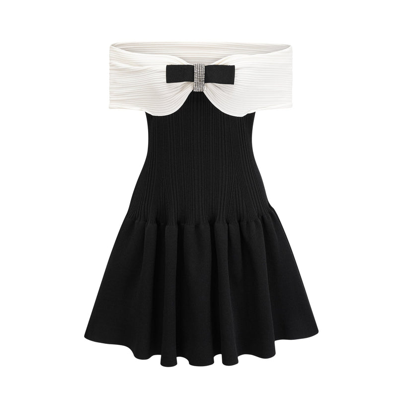 Miracle Mini Dress in Black & White off-shoulder design with crystal bow accent, thigh-length with contrasting colors and crystal embellishments, model 5'10' wearing size M, knitted construction blend of 51% Viscose, 35% Terylene, 13% Nylon, and 2% Elastane