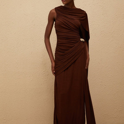 Nora Maxi Dress in Brown Sleeveless Bateau Neck Fitted Waistline Knitted Construction Asymmetrical Ruched Detailing Ribbon Design Silver-tone Hardware Side Zip Fastening Maxi Length