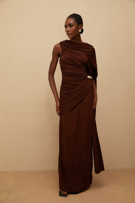 Nora Maxi Dress in Brown Sleeveless Bateau Neck Fitted Waistline Knitted Construction Asymmetrical Ruched Detailing Ribbon Design Silver-tone Hardware Side Zip Fastening Maxi Length