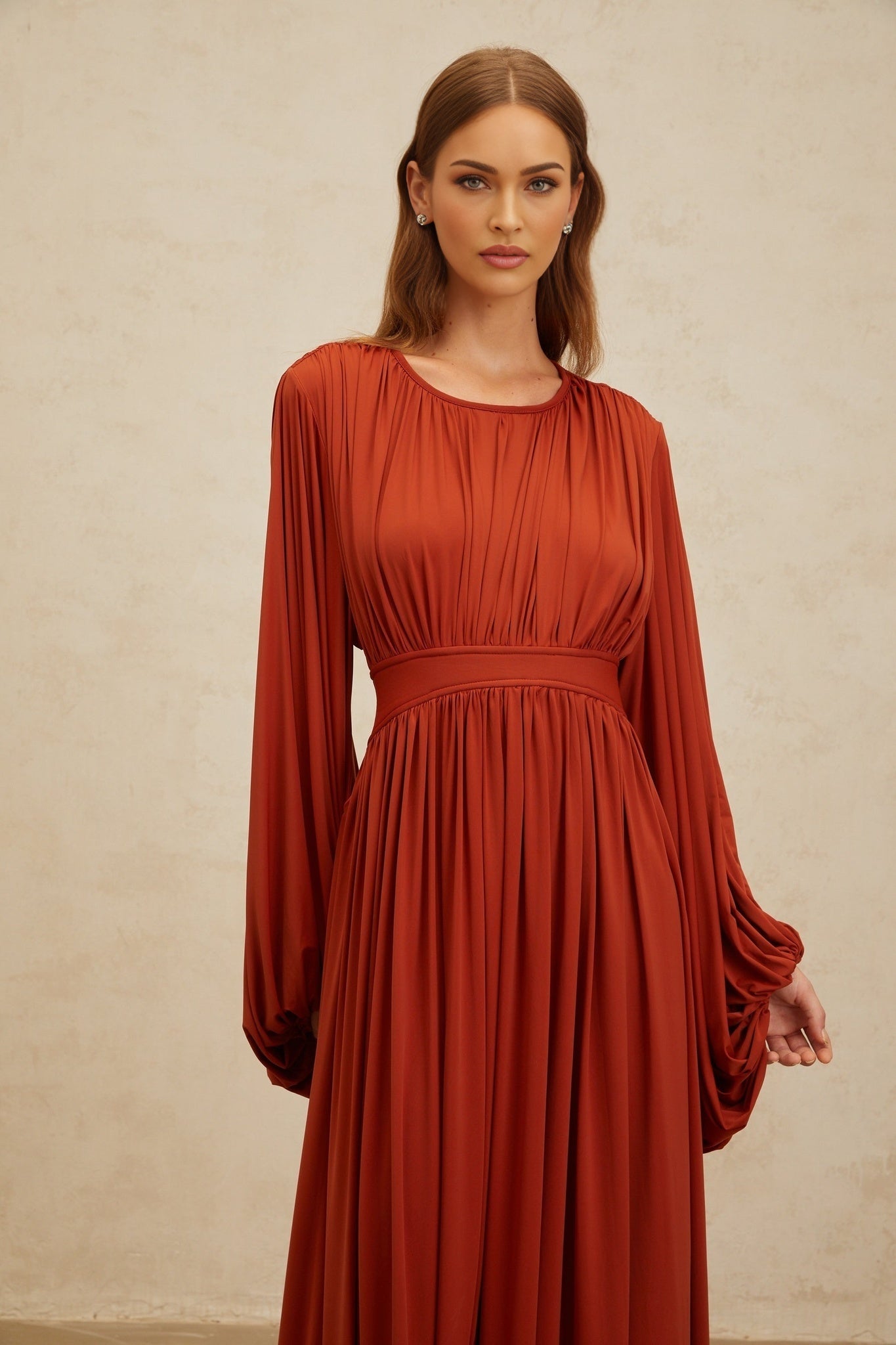 Orange maxi dress with long puff sleeves, cinched waist, and pleated detailing