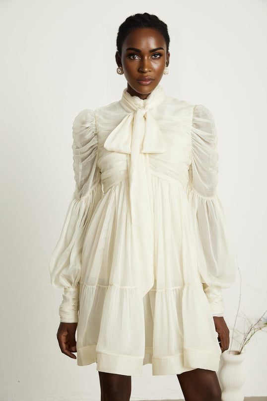 Paola Mini Dress in Neutrals sophisticated and stylish mock neck long puff sleeves buttoned cuffs tuck detailing gathered design pleated skirt rear zip fastening luxurious blend of Terylene fiber and Spandex timeless beauty