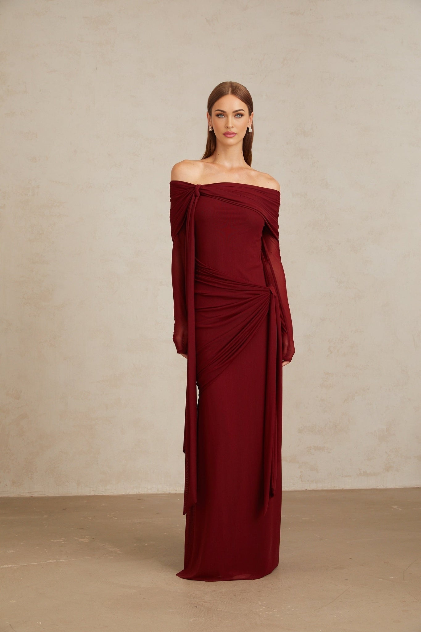 Red off the shoulder long sleeve dress with front tie detail and pleated, asymmetrical, ruched, and draped detailing