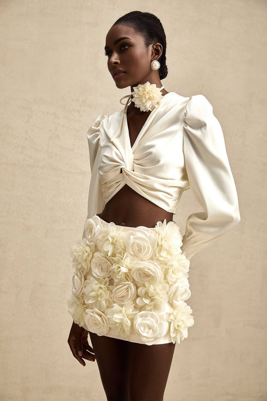 Short white top with twisted pattern and decorative artificial flowers