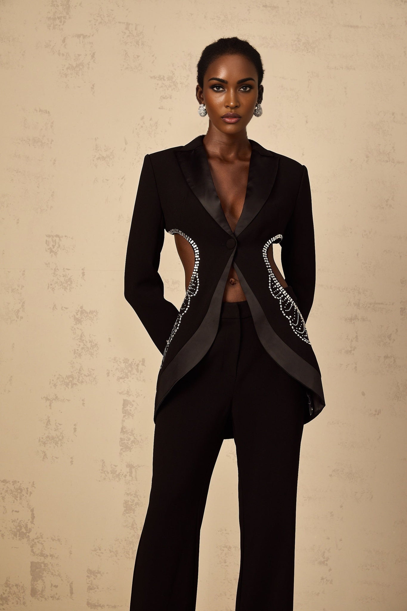 Stylish black blazer and trouser set with cutout details and embellishments on a white background
