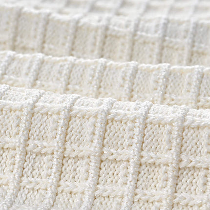 Textured white knitted jacket with black trim and decorative buttons paired with a ruffled hem skirt
